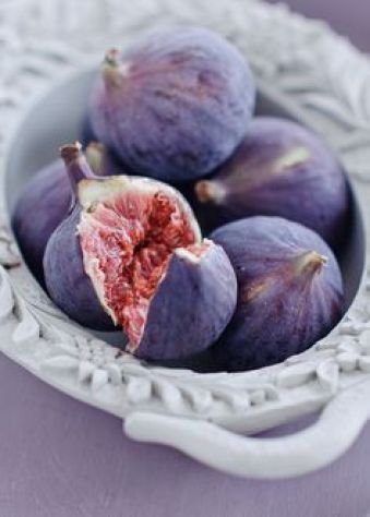 Bowl of fresh figs, one broken open to show red flesh.